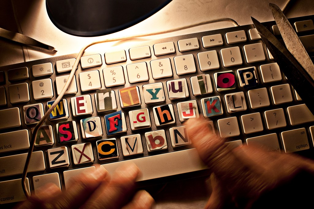 Hands Typing on Computer Keyboard that has cut out letter covering the normal letters